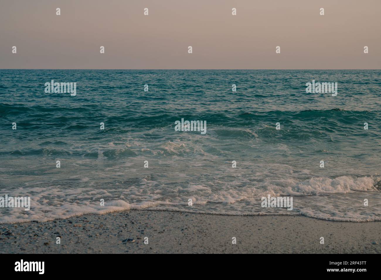 Wellen des Mittelmeers, die sich zum türkischen Sandstrand hin bewegen. Schöner türkischer Abend. Stockfoto