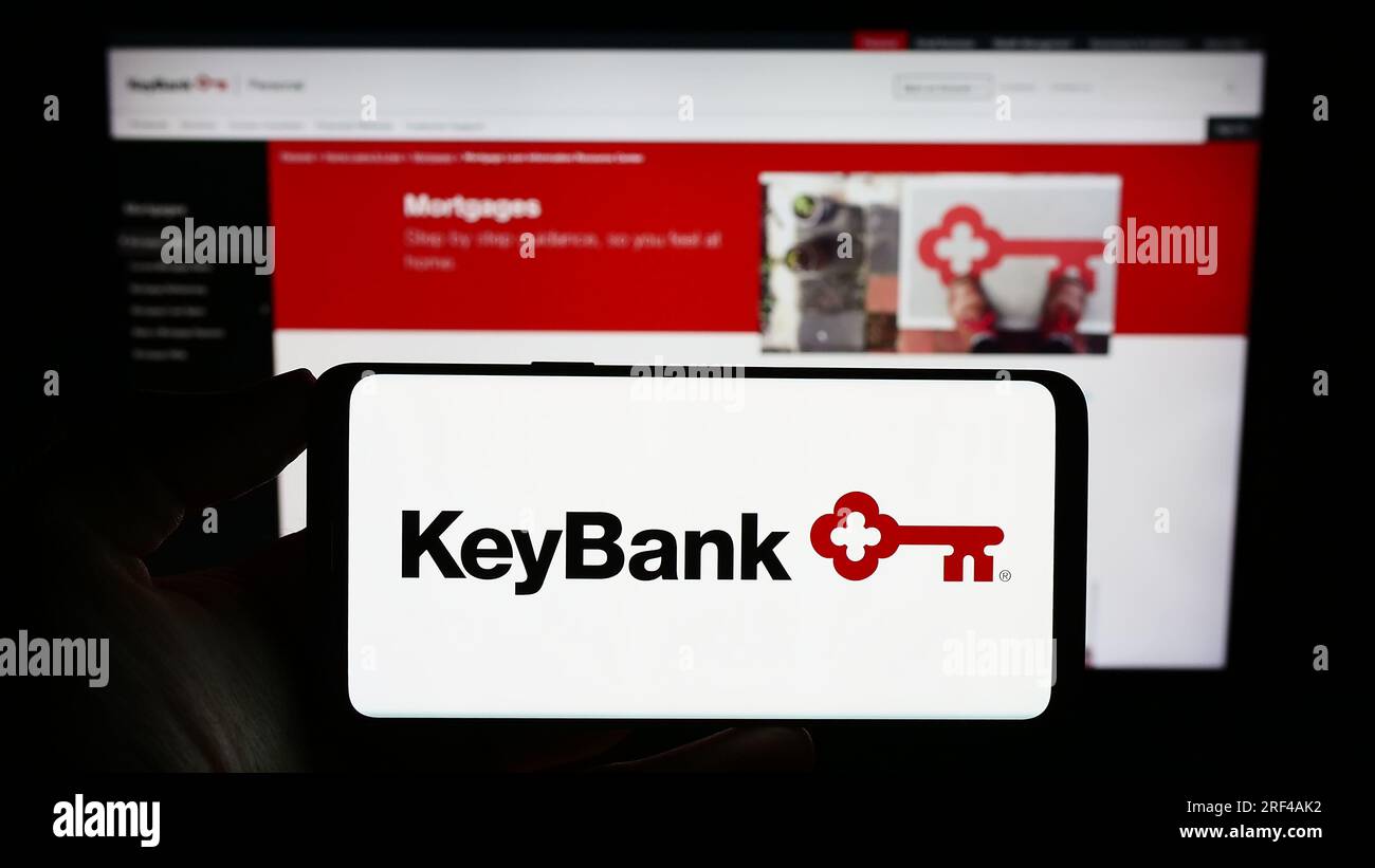 Person, die ein Mobiltelefon mit dem Logo des amerikanischen Finanzunternehmens KeyCorp (KeyBank) auf dem Bildschirm vor der Webseite hält. Konzentrieren Sie sich auf das Display des Telefons. Stockfoto