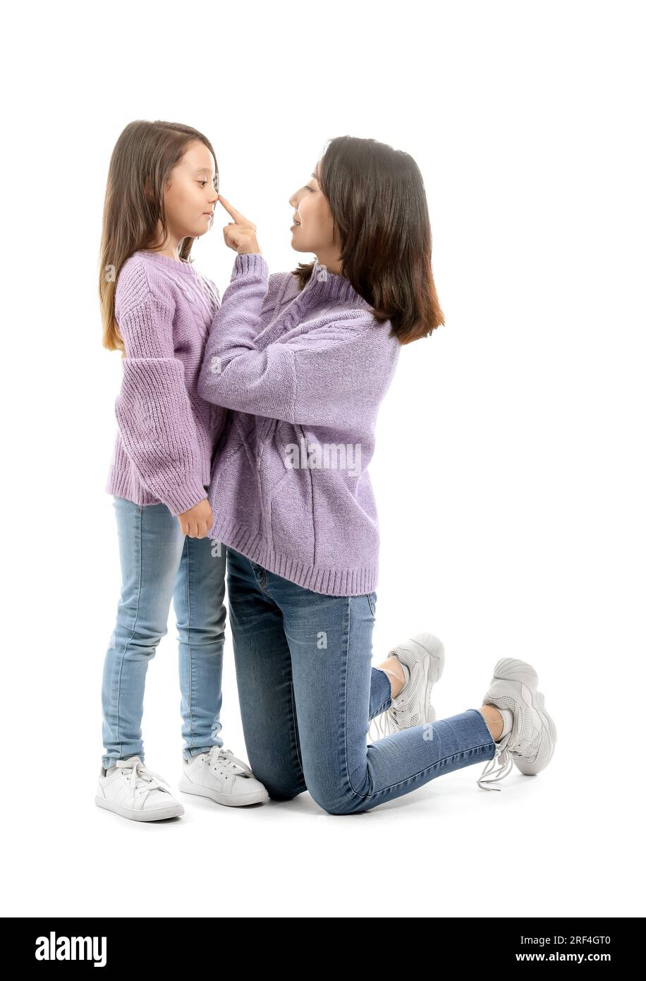 Asiatische Mutter berührt die Nase ihrer kleinen Tochter auf weißem Hintergrund Stockfoto