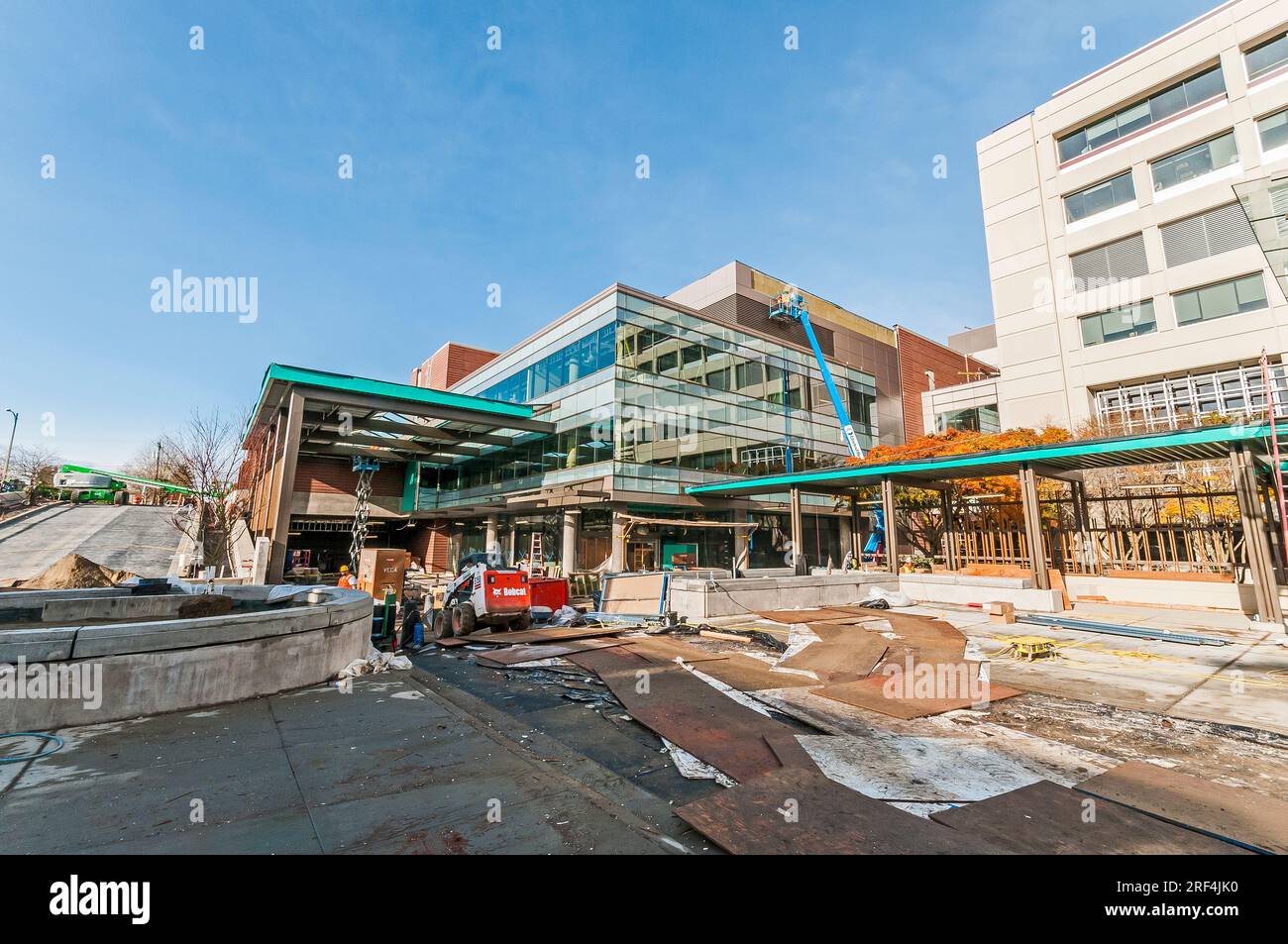 Bauarbeiter auf einer Baustelle für eine Gesundheitseinrichtung. In der Abbildung ist ein Kompaktlader von Bobcat zu sehen. Stockfoto
