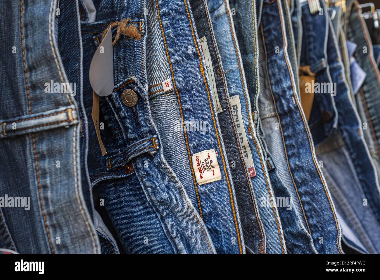 Viele Jeans hängen an einem Ständer. Jeans hängen im Laden. Jeans oder Jeans, die in einem Bekleidungsgeschäft an einem Kleiderbügel hängen. Konzept des Einkaufs, Verkaufs Stockfoto