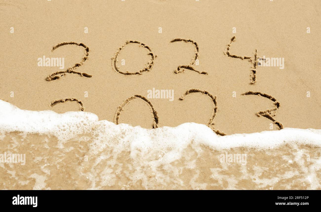 Symbol für das neue Jahr 2024. Die Welle wäscht die Inschrift 2023 weg. Stockfoto