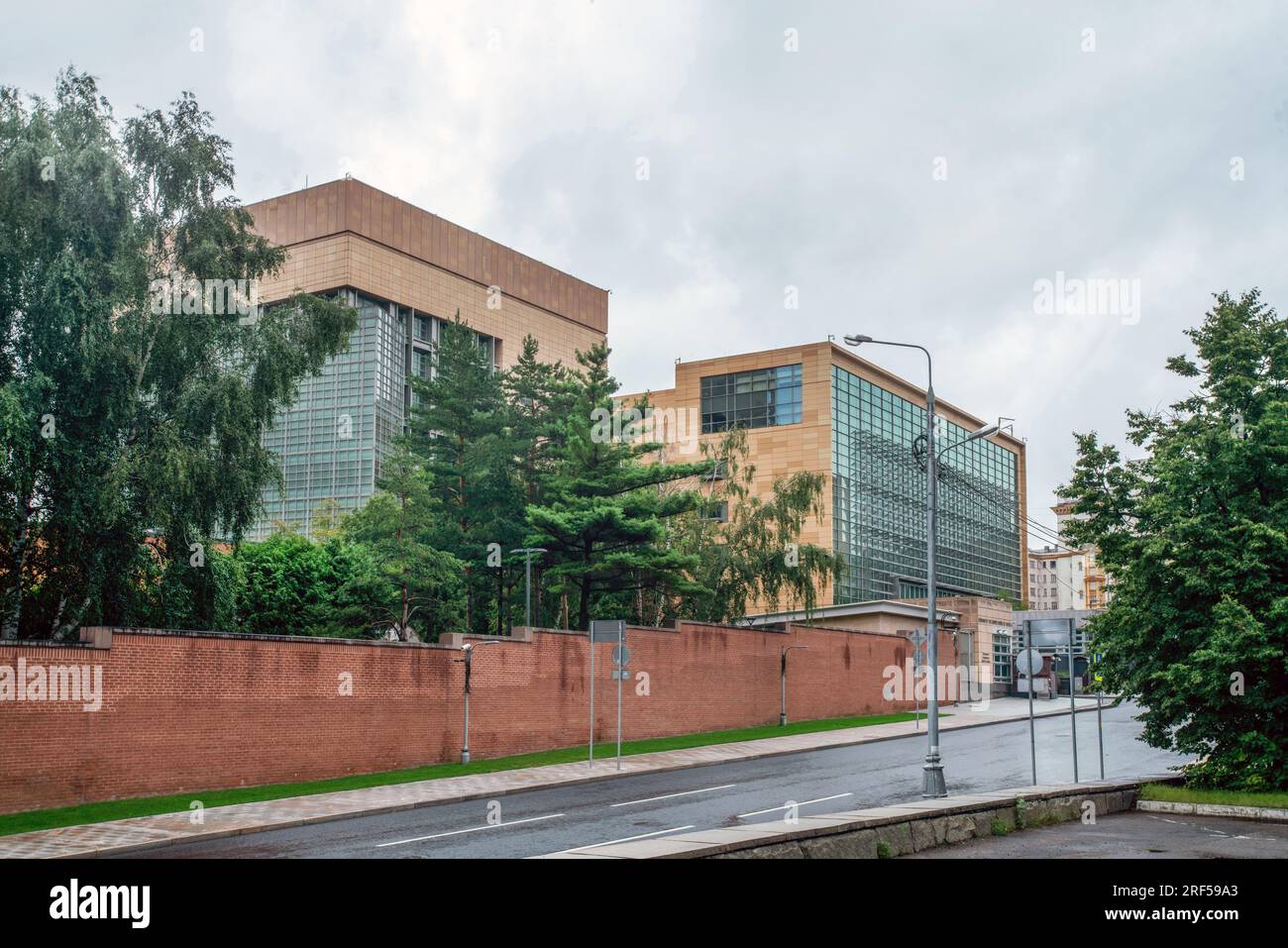 07-29-2023 Moskau Russland. Seitlicher Blick auf US-Botschaftsgebäude in Moskau mit Park auf einem Gebiet mit fantastischen Birken- und Fichtenbäumen Hochziegel Stockfoto