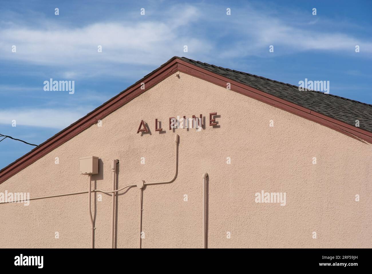 Alpine Schriftzeichen und Schatten am Giebelende des Amtrak-Bahnhofs mit Stuckseite unter blauem Himmel Stockfoto