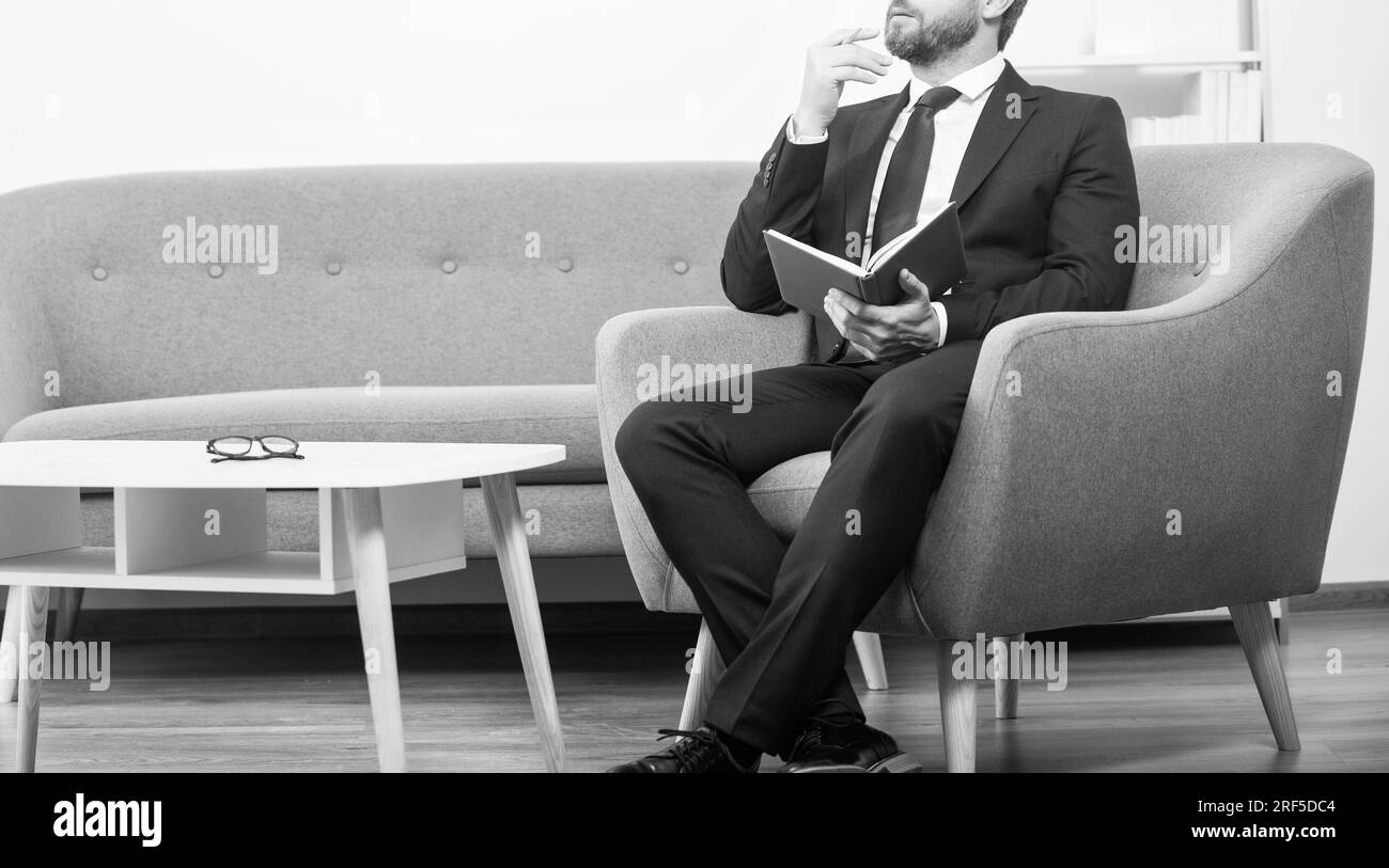 Reifer Geschäftsmann im Anzug sitzen im Büro mit Planer. Kognition Stockfoto