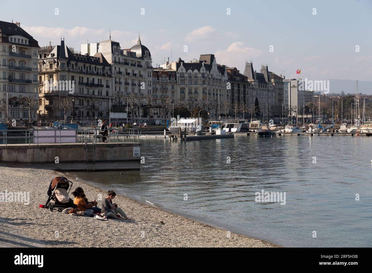 Genf, Schweiz - 25. März 2022: Menschen genießen den malerischen Blick auf den Genfer See an der Bucht von Genf, dem französischen Teil der Schweiz. Stockfoto