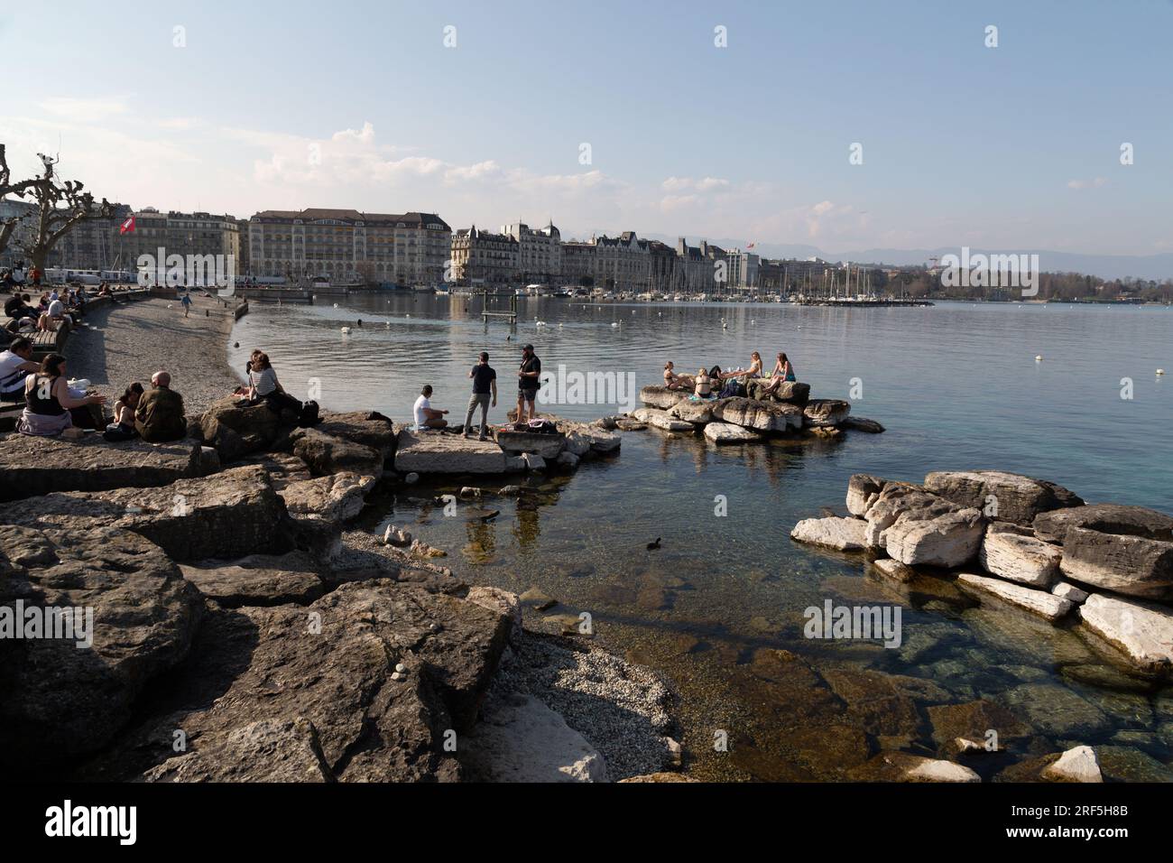 Genf, Schweiz - 25. März 2022: Menschen genießen den malerischen Blick auf den Genfer See an der Bucht von Genf, dem französischen Teil der Schweiz. Stockfoto