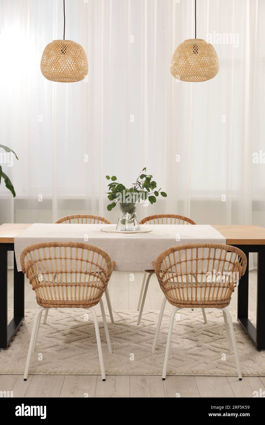 Vase mit Eukalyptusästen auf Tisch und Stühlen im Speisesaal Stockfoto