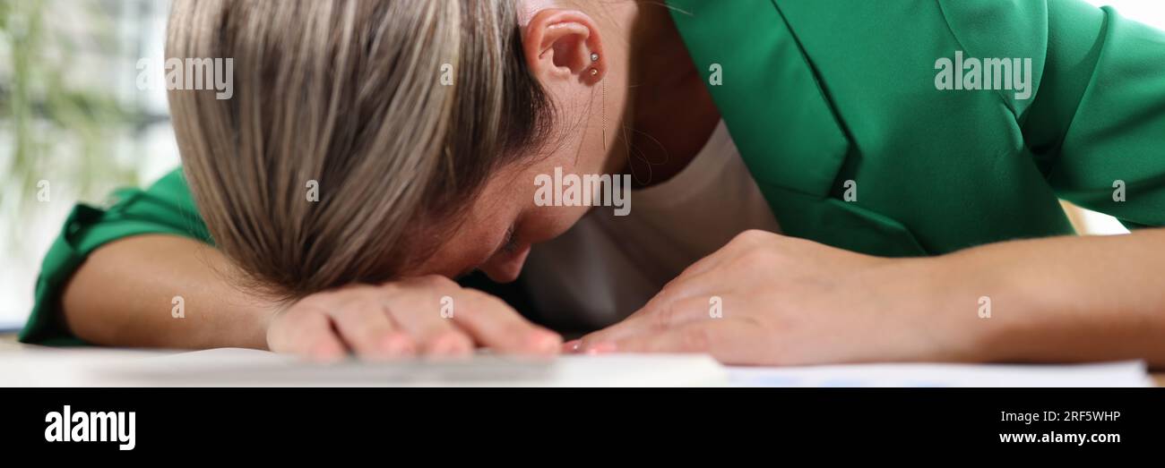 Erschöpfte und müde Frau, die im Büro auf ihrem Schreibtisch schläft. Stockfoto