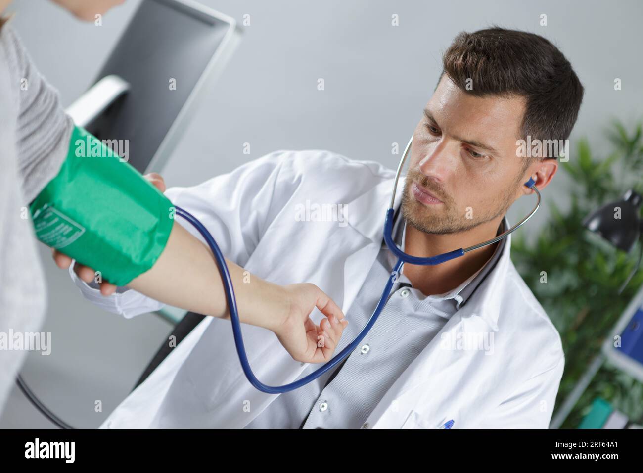 Der männliche Arzt überprüft den Blutdruck des Patienten Stockfoto