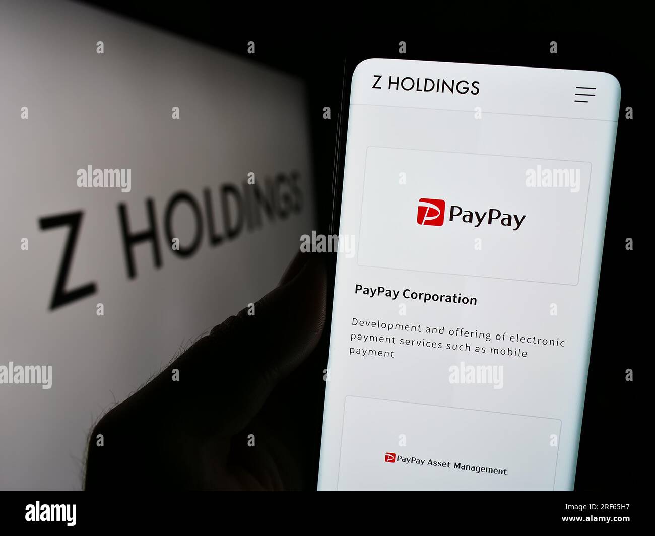 Person mit Smartphone und Website der japanischen Z Holdings Corporation auf dem Bildschirm vor dem Logo. Konzentrieren Sie sich auf die Mitte des Telefondisplays. Stockfoto