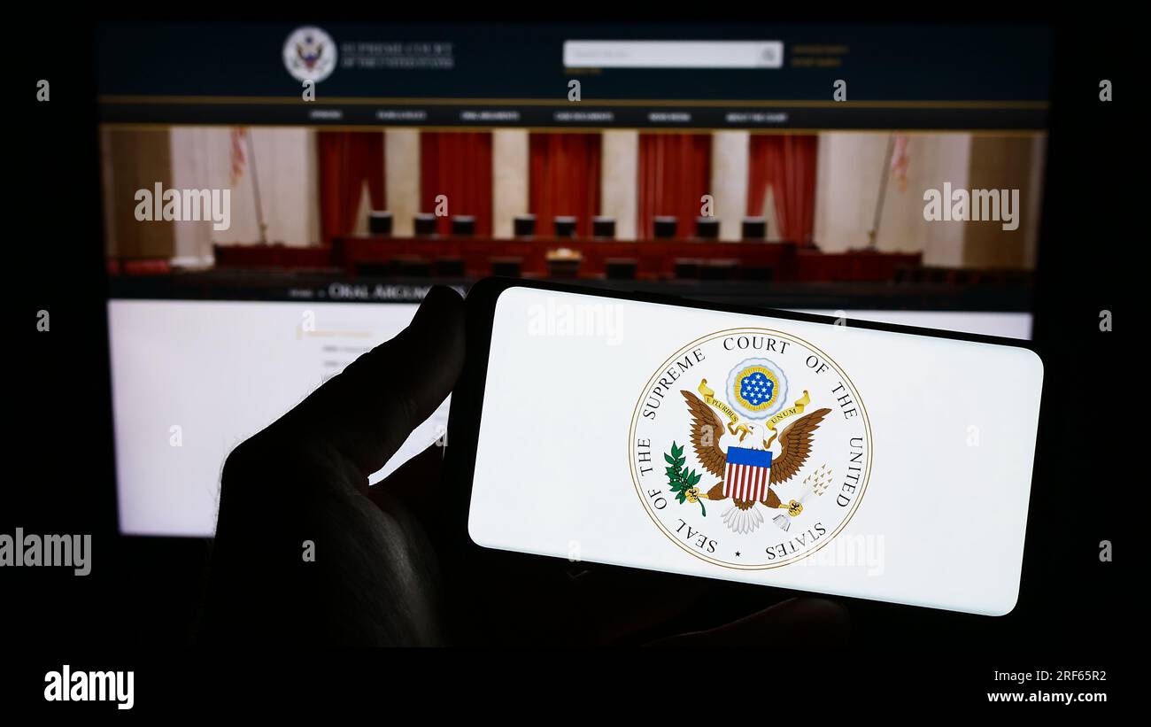 Person, die ein Smartphone mit US-Siegel hält Supreme Court (SCOTUS) auf dem Bildschirm vor der Website. Konzentrieren Sie sich auf das Display des Telefons. Stockfoto