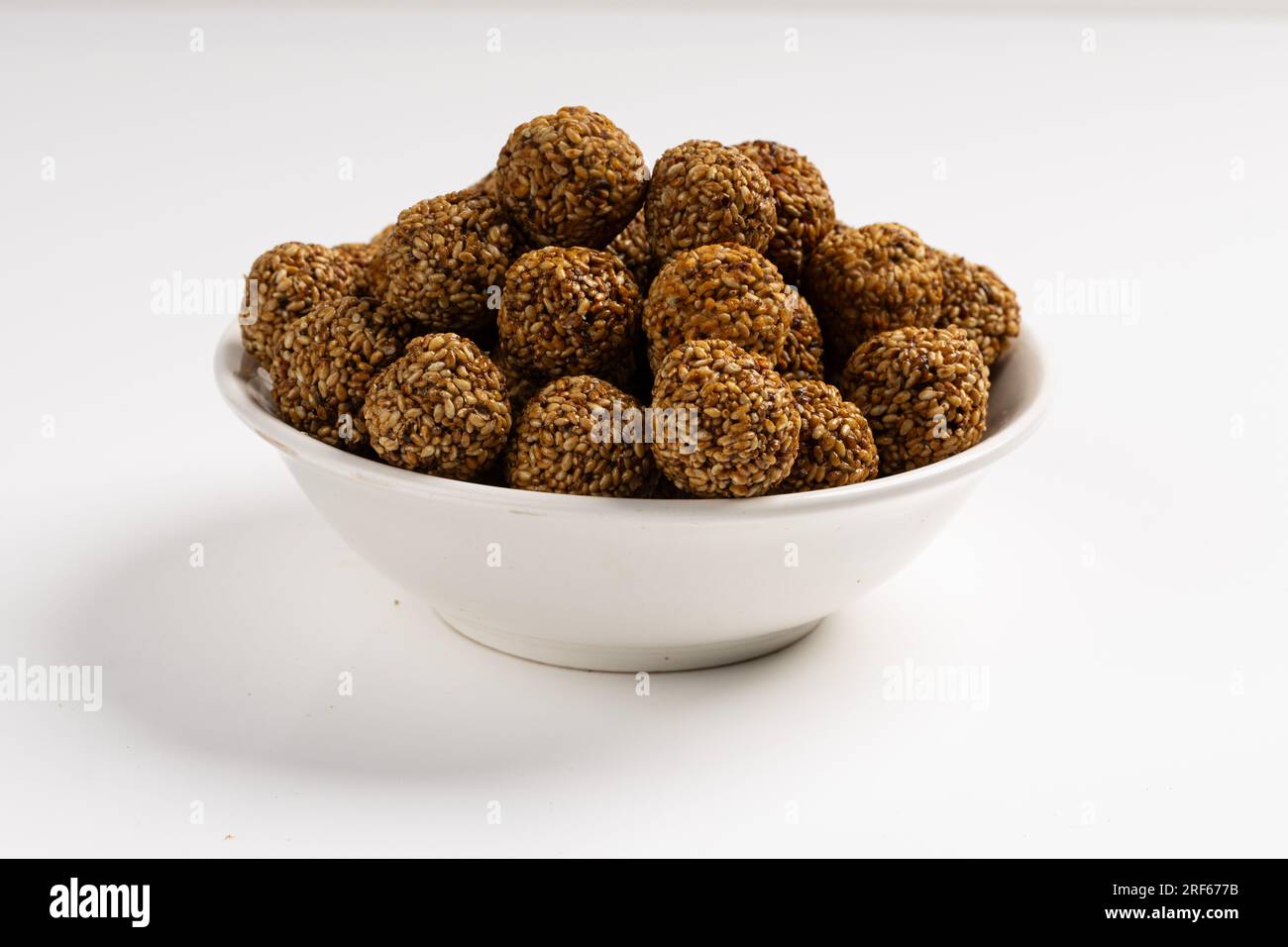 Sesam Ladoo oder Ellunda oder Til ladoo, ein traditionelles indisches süßes Leckerli aus Sesamsamen und Zierkerzen, isoliertes Bild mit weißem Hintergrund. Stockfoto