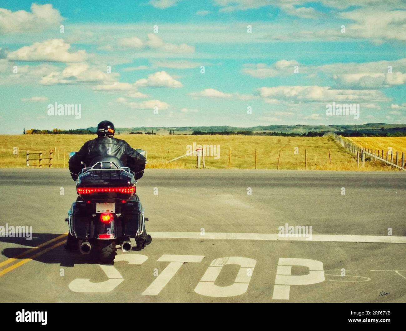 Ein Motorrad mit einem Fahrer an einer Haltelinie auf einer Schnellstraße im Turner Valley, Alberta, Kanada. Road Trip Journey, Urlaub in kanadischer Landschaft, lan Stockfoto