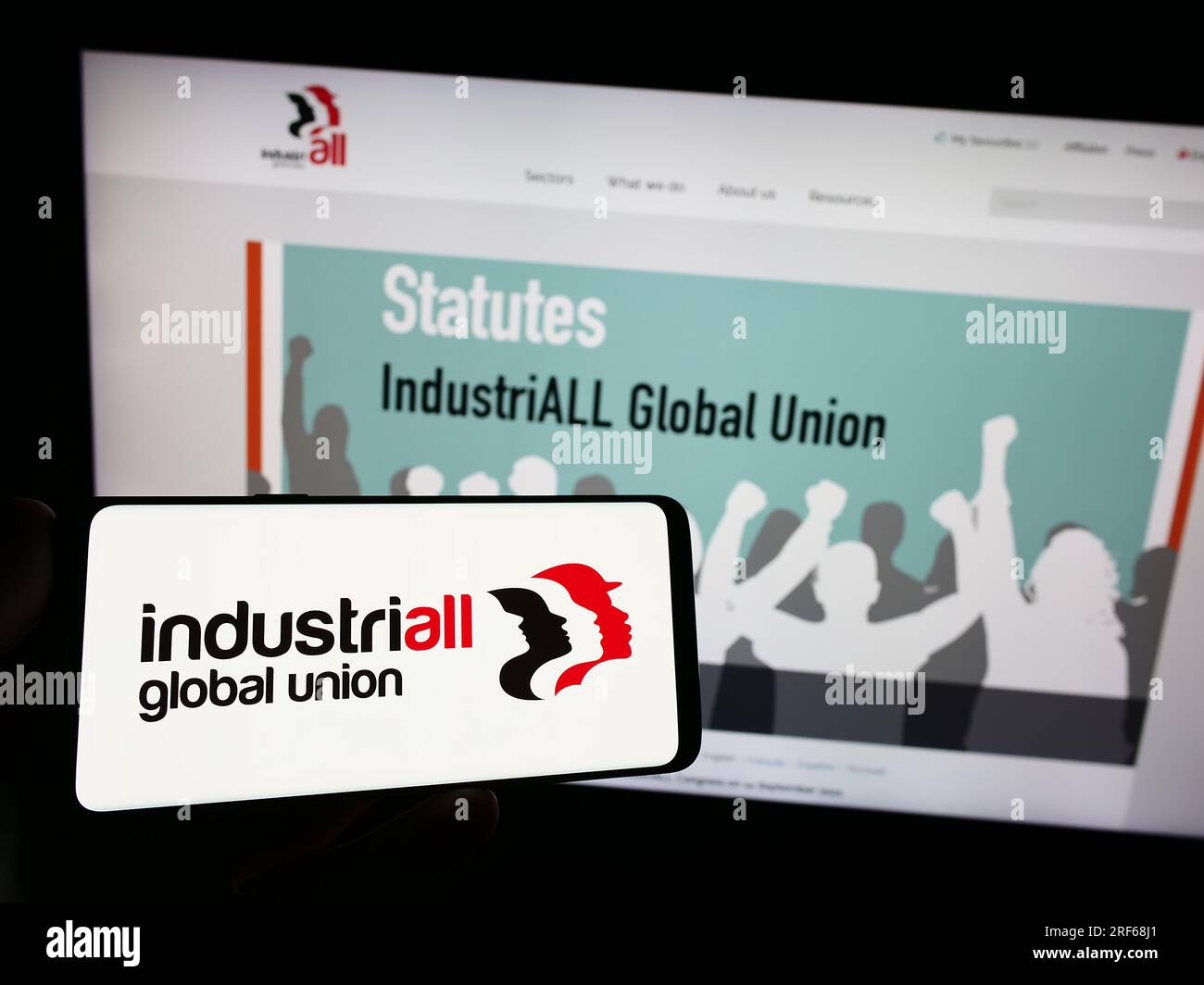 Person, die ein Smartphone mit dem Logo der Organisation IndustriALL Global Union auf dem Bildschirm vor der Website hält. Konzentrieren Sie sich auf das Display des Telefons. Stockfoto