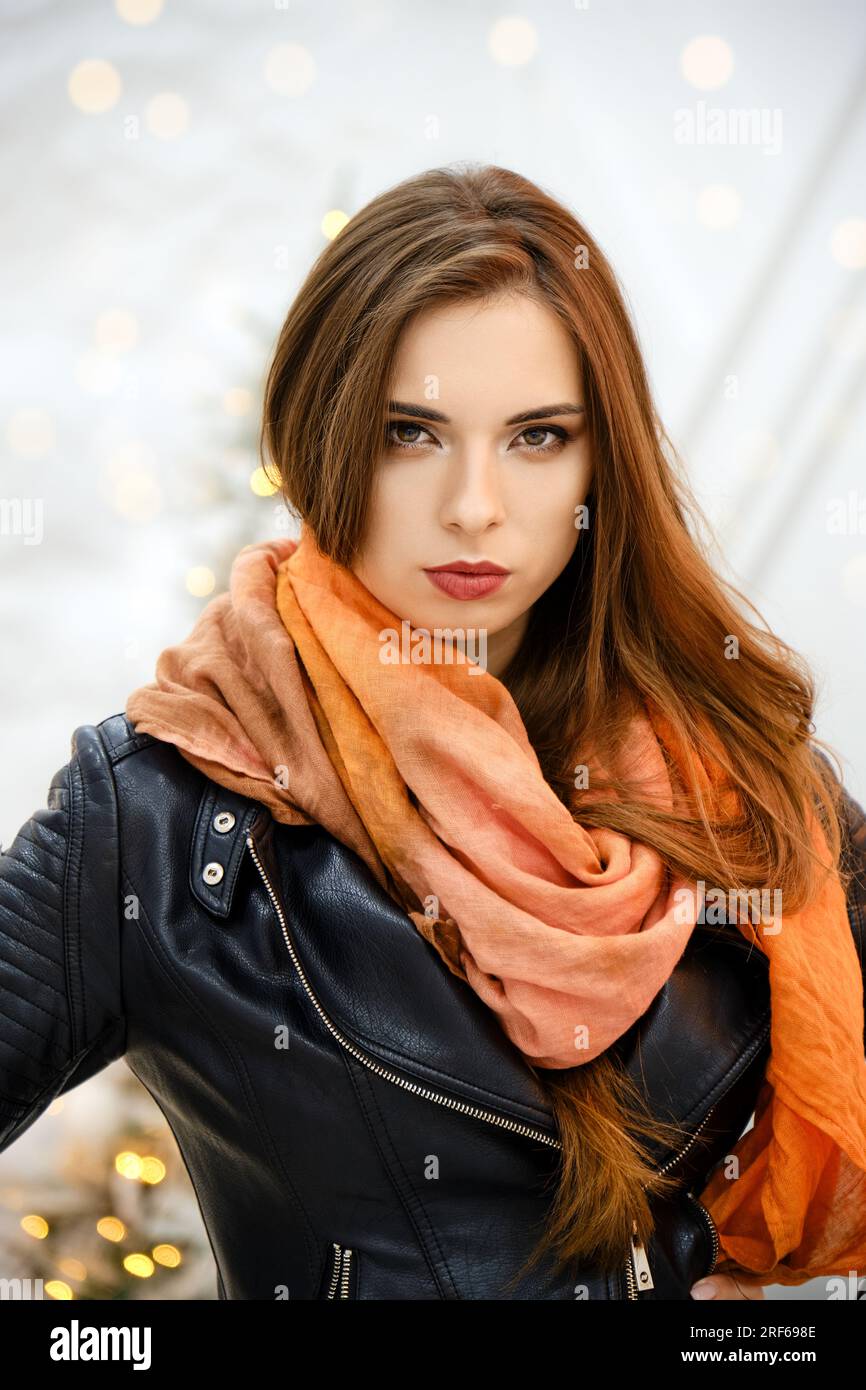Eine stilvolle Frau in einem orangefarbenen Kopftuch, das um ihren Kopf gewickelt ist, sieht streng aus Stockfoto