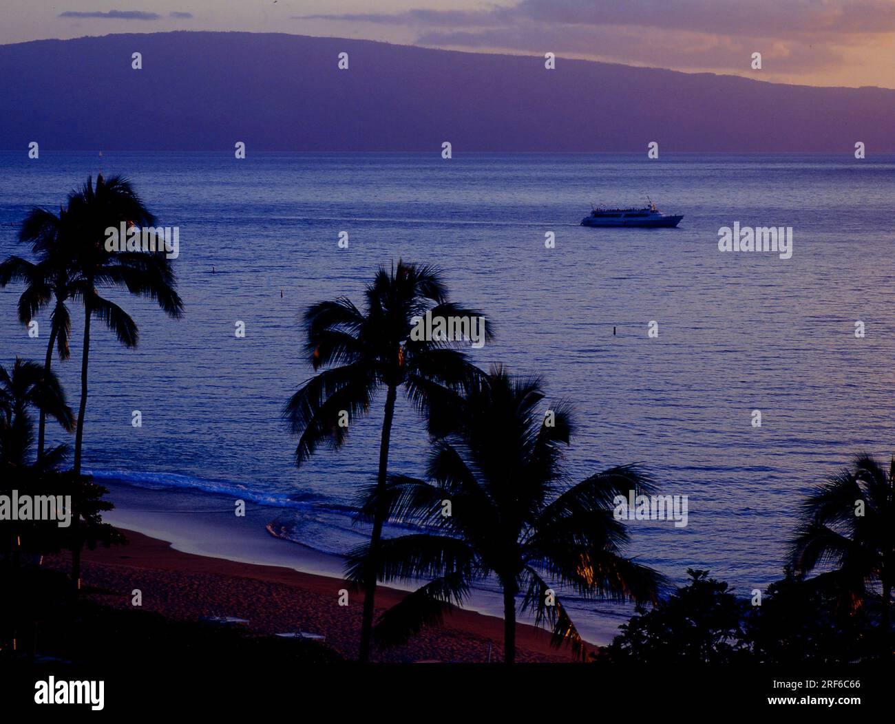 Blick in den Park des Hotel Royal Lahaina Resort im Westen der Insel und über Kaanapali Beach zur benachbarten Insel in der Abenddämmerung. USA- Stockfoto