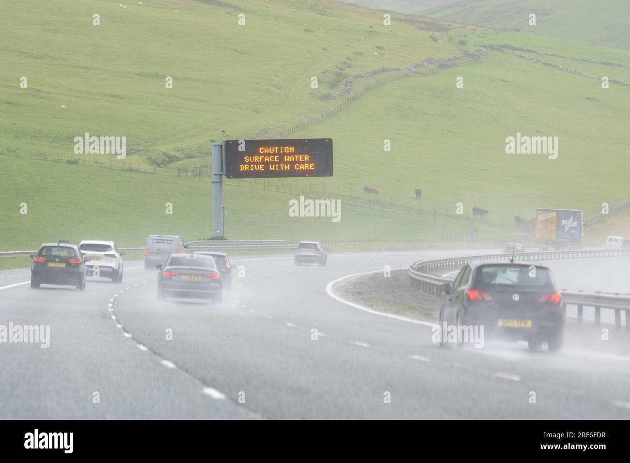 Oberflächenwasser auf der britischen Autobahn - Vorsicht Oberflächenwasser fahren mit Achtung Schild - Schottland, Großbritannien Stockfoto
