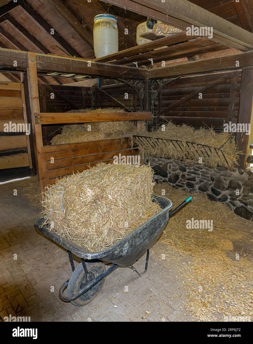 Eine Schubkarre mit Heu in einer leeren Scheune Stockfoto