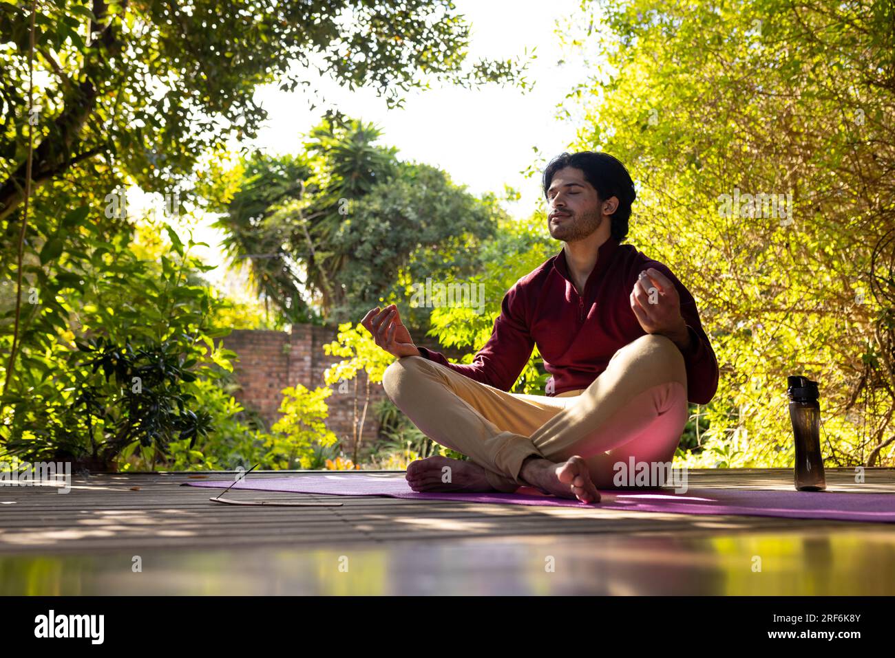 Fokussierter indischer Mann, der Yoga-Meditation auf einer sonnigen Terrasse praktiziert, Kopierraum Stockfoto