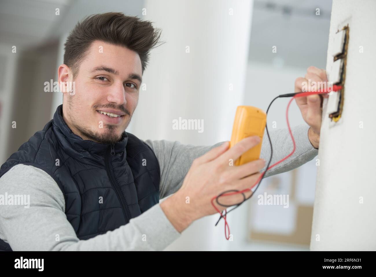 Elektriker, der den Spannungspegel in den Steckdosenkabeln überprüft Stockfoto
