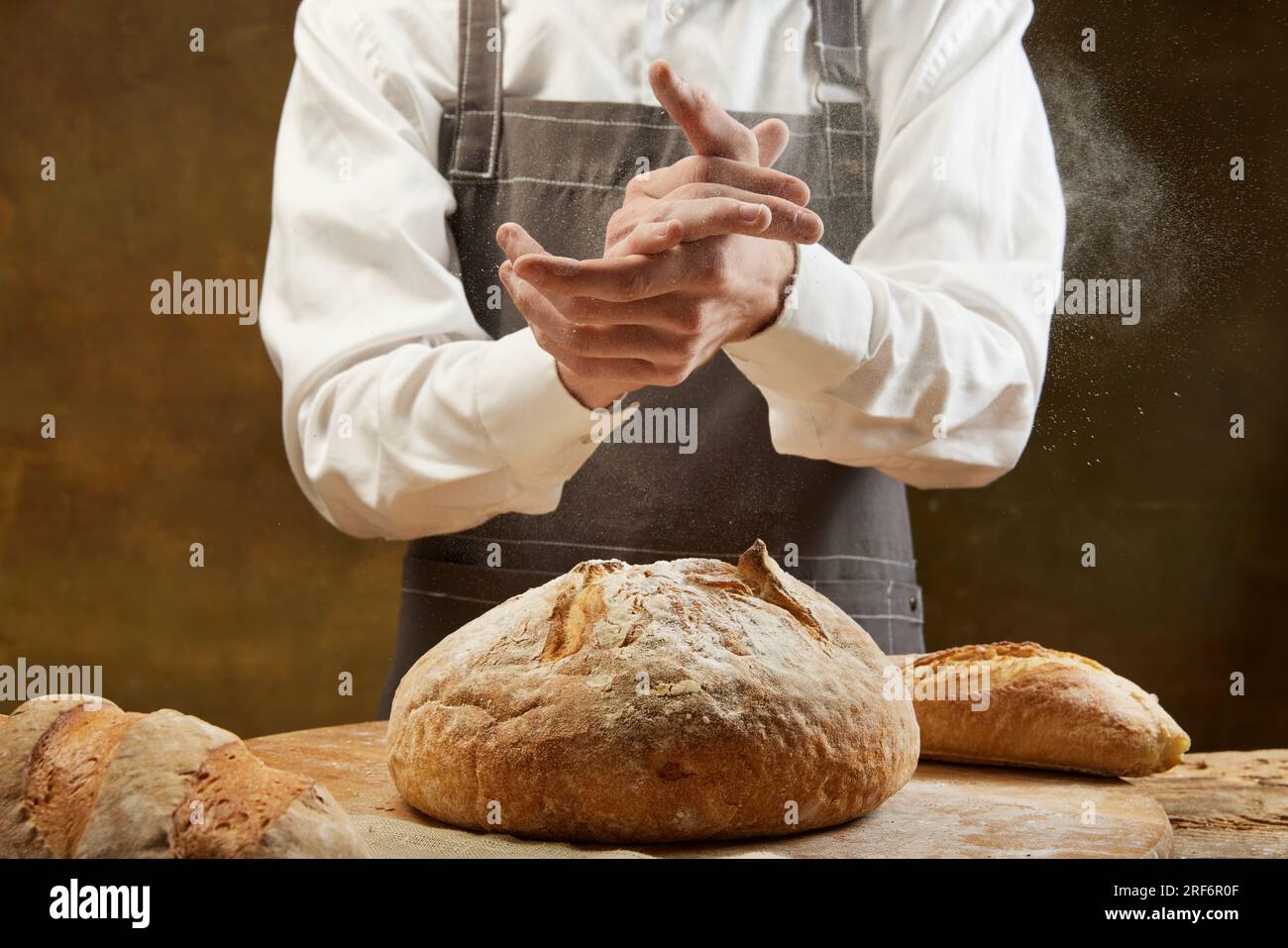 Bäcker, der Brot kocht. Der Mann schlägt Mehl über den Teig. Männerhände mit Mehl-Tripper. Stockfoto