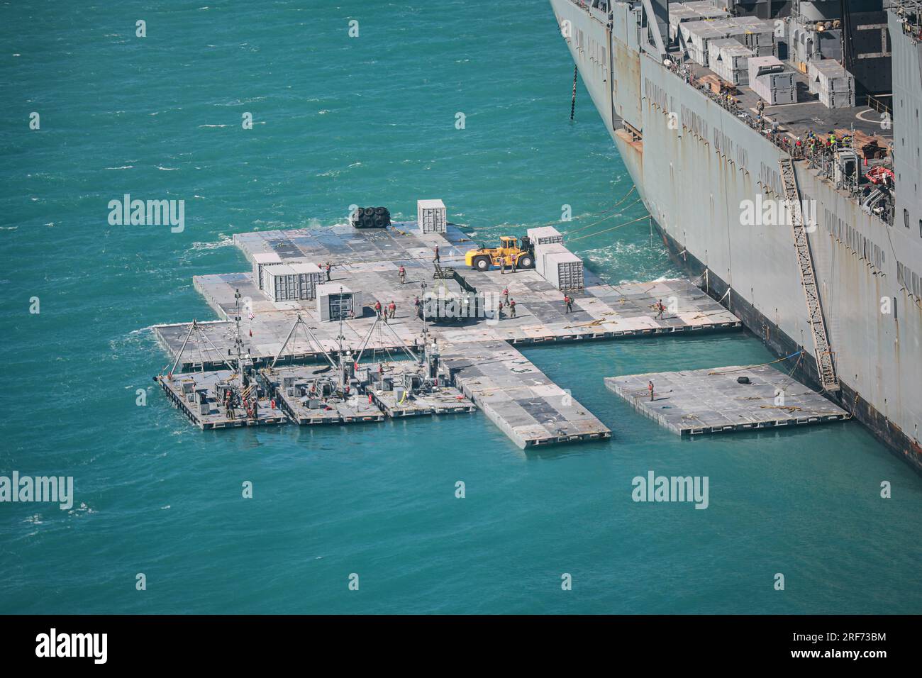 Marinesoldaten der 368. Seaport Operations Company und 331. Transportation Company bauen am 29. Juli 2023 einen Damm neben MV Maj. Bernard F. Fisher vor der Küste von Bowen, Australien. Wenn der Damm fertig ist, wird er einen schwimmenden Pier bilden, der die Entladung von Fahrzeugen vom Fisher zum Ufer ermöglicht, was die kritische Fähigkeit von Joint Logistics Over-the-Shore während Talisman Sabre demonstriert. Talisman Sabre ist die größte bilaterale Militäraktion zwischen Australien und den Vereinigten Staaten mit multinationaler Beteiligung, die einen freien und offenen Indo-Pacific von strengt vorantreibt Stockfoto