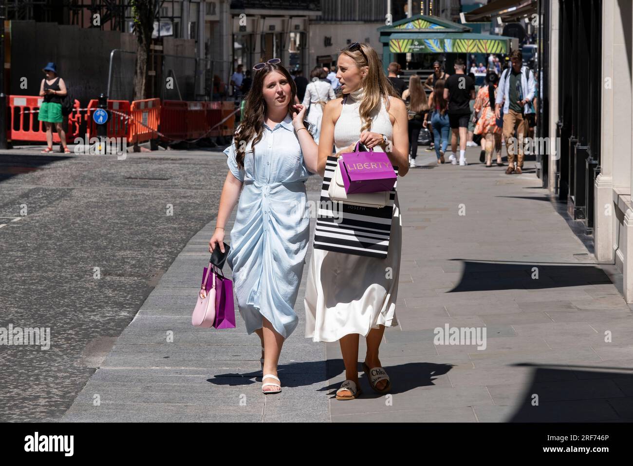 Zwei Käufer in der Bond Street mit ihren Liberty-Taschen am 7. Juli 2023 in London, Großbritannien, im exklusiven Bereich von Mayfair. Traditionell wohlhabende Teile von West London haben sich zu wohlhabenden Spielplätzen der Superreichen entwickelt, mit Zuströmen von ausländischem Geld, insbesondere aus dem Nahen Osten, Russland und China. Jüngsten Untersuchungen zufolge sind in der britischen Hauptstadt mehr Menschen mit hohem Nettowert und ultrahohem Nettowert als in jeder anderen Stadt der Welt zu Hause. Stockfoto