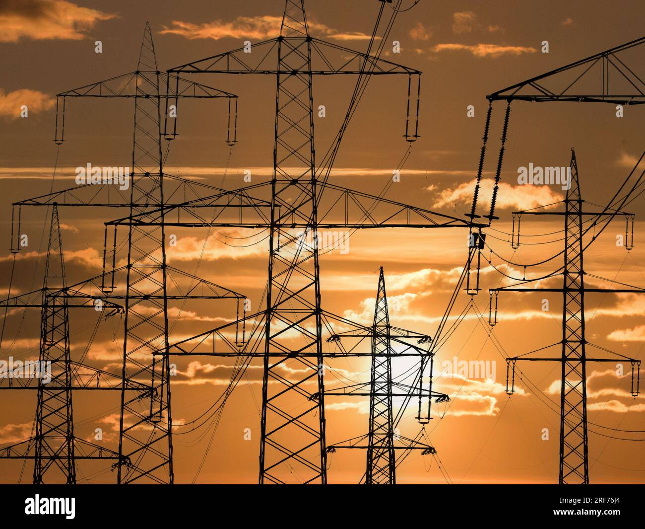 Strommasten einer Hochspannungsleitung für elektrischen Strom vor Sonnenuntergang, Stockfoto