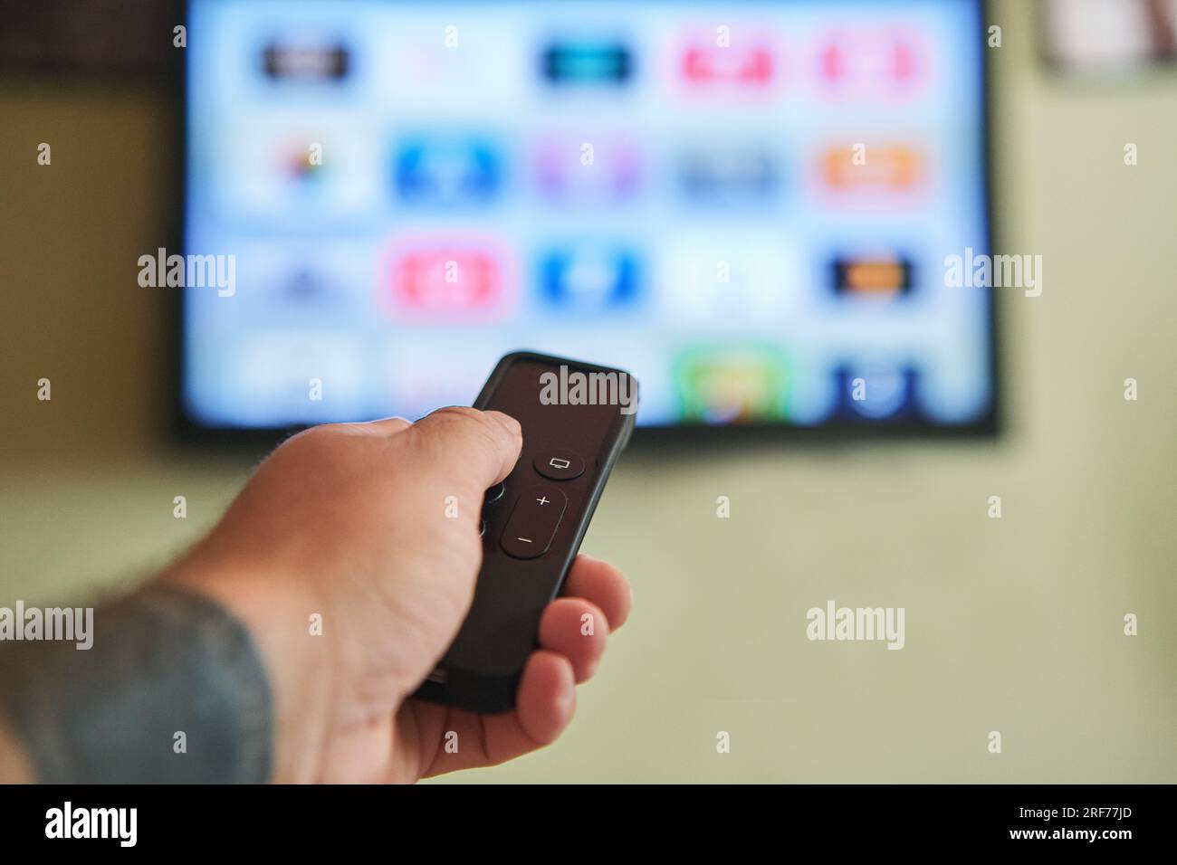 Multimedia-Streaming-Konzept. Fernbedienung mit Handbedienung. TV-Bildschirm mit vielen Bildern. Stockfoto