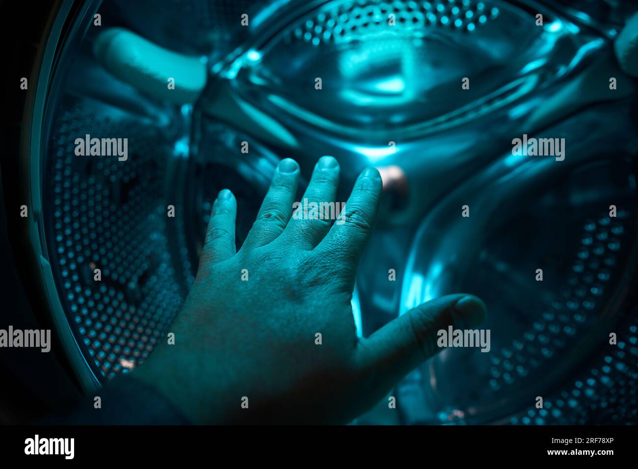 Eine Hand in der Waschmaschine in blauem Licht, Zukunft, Science-Fiction, Konzept Stockfoto
