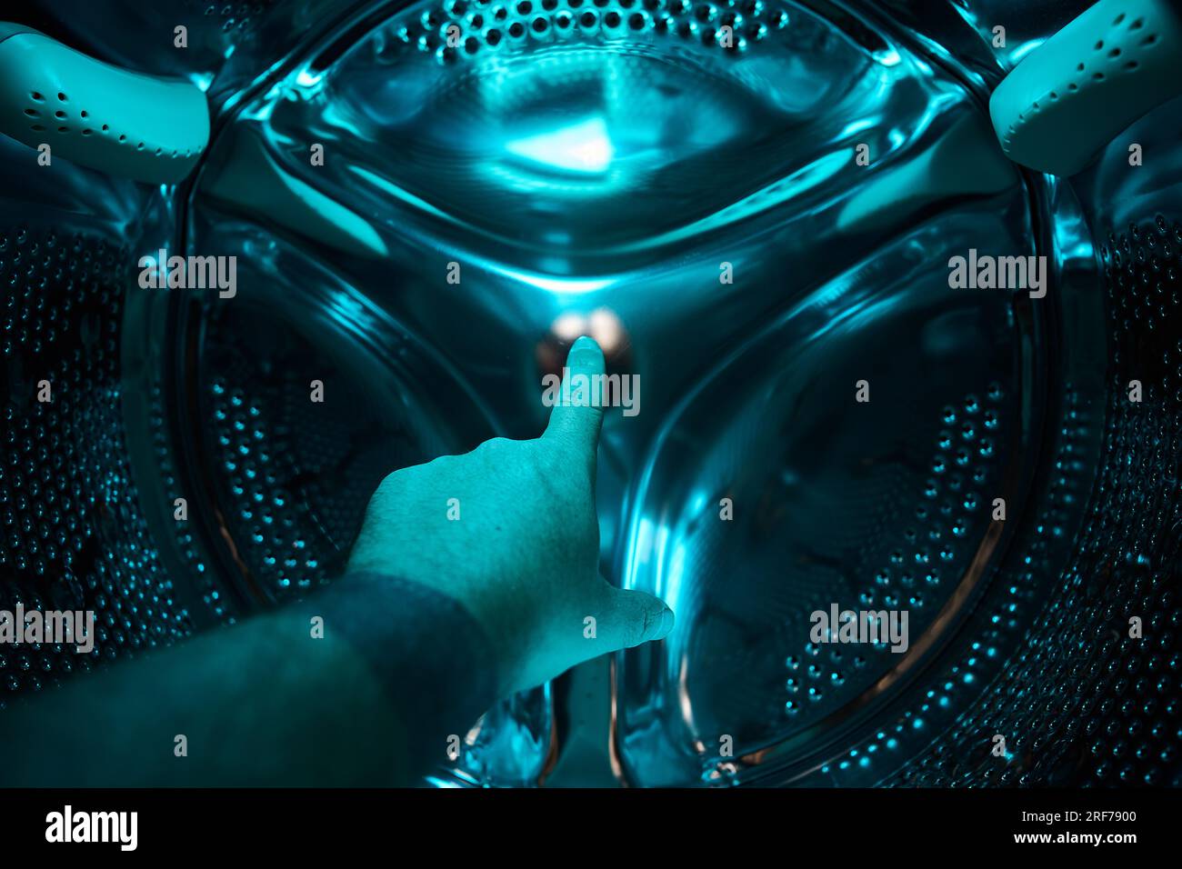 Eine Hand in der Waschmaschine zeigt einen Finger in ein blaues Licht, Zukunft, Science-Fiction, Konzept Stockfoto