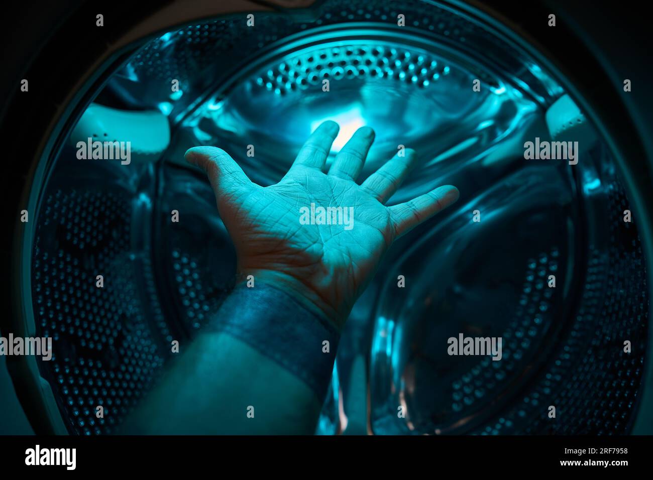 Eine Hand in der Waschmaschine in blauem Licht, Zukunft, Science-Fiction, Konzept Stockfoto