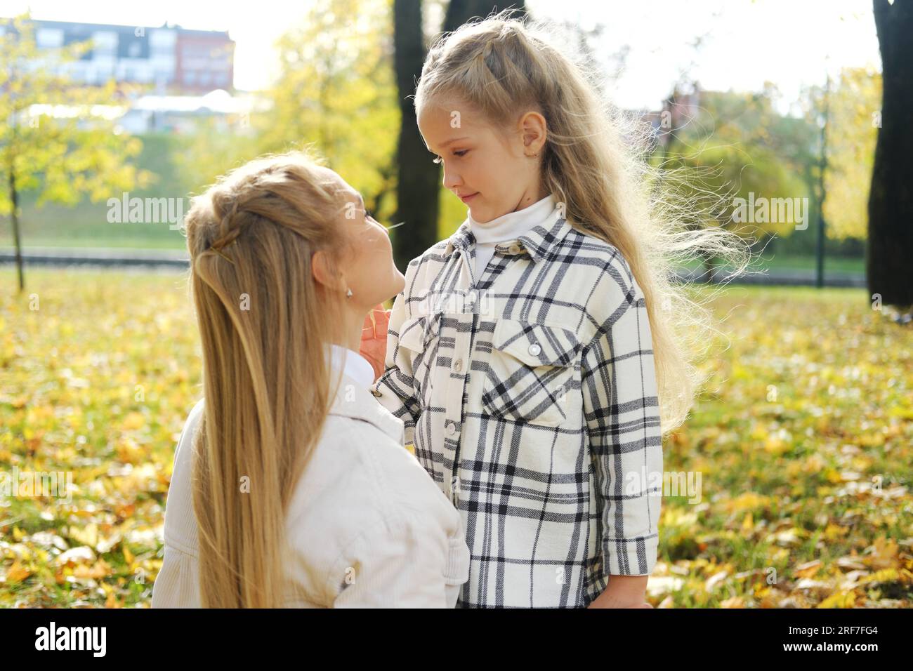 Mutter und Tochter verbringen Zeit zusammen im Herbstpark. Mutter sieht ihre Tochter liebevoll an. Horiontalfoto Stockfoto