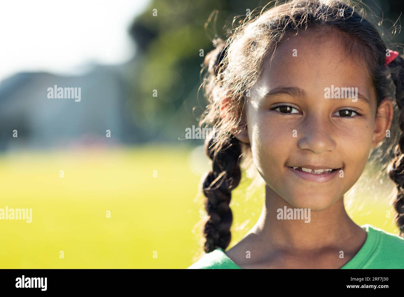 Porträt einer birassischen Schulmädchen, die auf einem sonnigen Sportplatz lächelt, Kopierraum Stockfoto