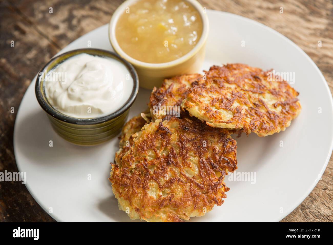 Hausgemachte polnische Kartoffelpfannkuchen aus geriebener Kartoffel, Mehl, Ei und Zwiebeln, die in Öl gebraten wurden. Serviert mit saurer Sahne und Apfelsauce. E Stockfoto