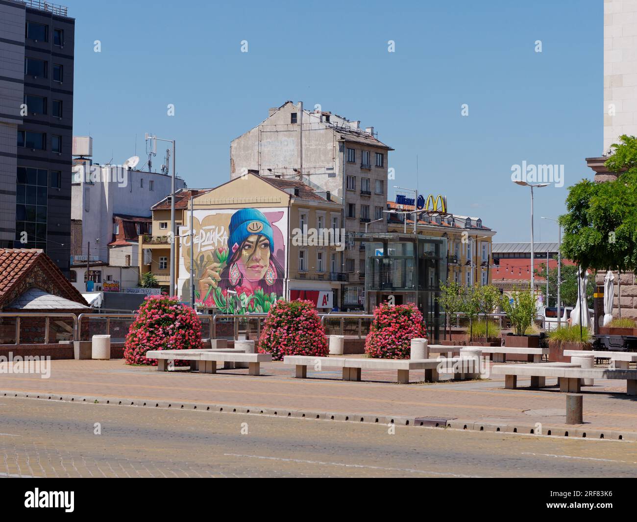 „Serdika Tulip“ von Arsek Erase Street Art in Sofia, Bulgarien. August 2023. Straßenbänke/Sitzplätze und Blumen im Vordergrund. Stockfoto