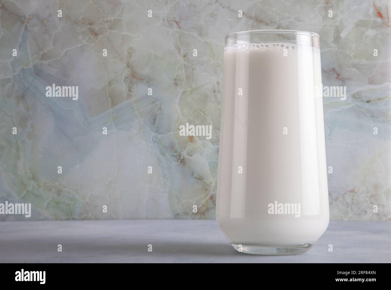 Ein Glas Milch auf einem blauen Tisch auf einem Marmorhintergrund, Kopierraum Stockfoto
