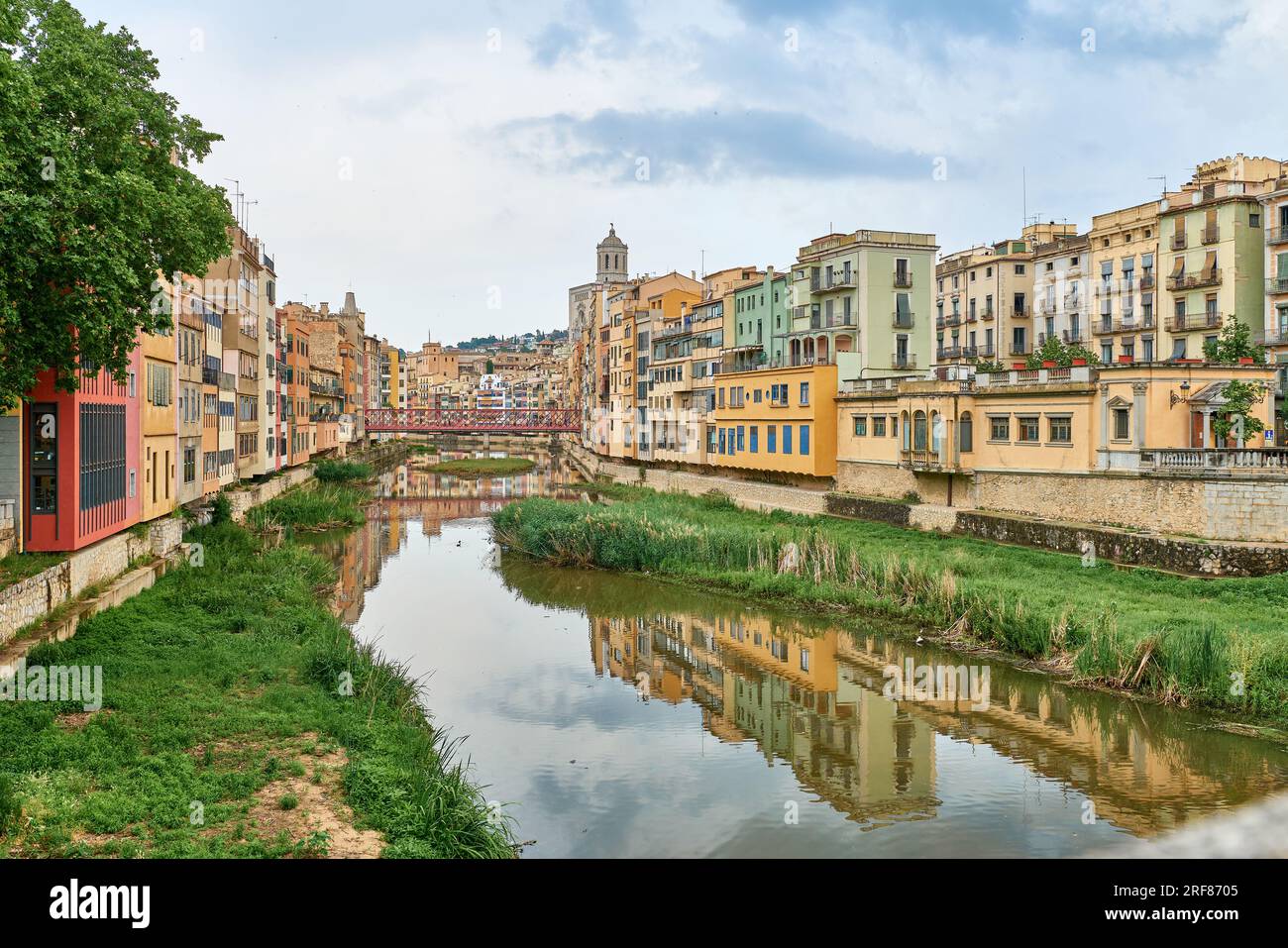 Farbenfrohe gelbe und orangefarbene Häuser und Brücke Pont de Sant Agusti spiegelten sich im Fluss Onyar in Girona, Katalonien, Spanien, wider. Kirche von Sant Feliu und Stockfoto