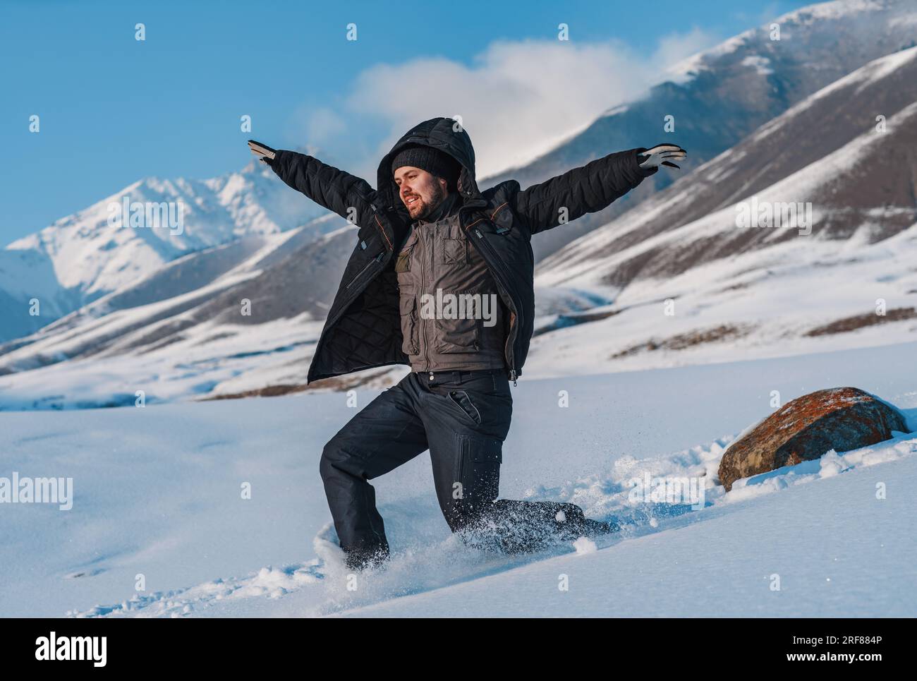 Junger Tourist, der in der Wintersaison vom Berg runterrutscht Stockfoto