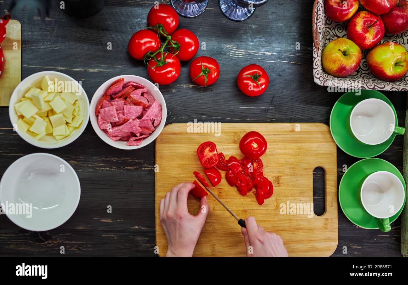 Frau kocht in der Küche, geschnittene Zutaten und Hand mit Messer Draufsicht Stockfoto