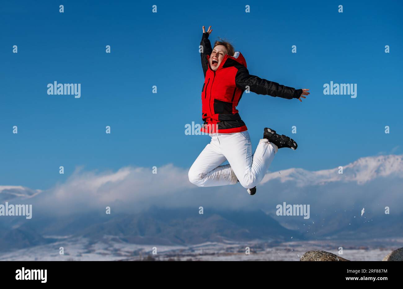 Junge, glückliche Frau, die im Winter in den Bergen hüpft Stockfoto