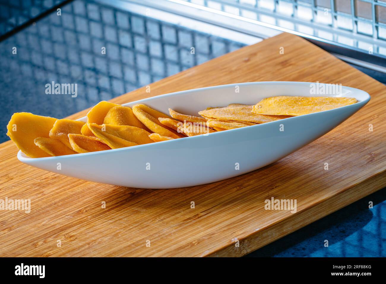 Küchentisch mit getrockneter Mango in Schüssel Stockfoto