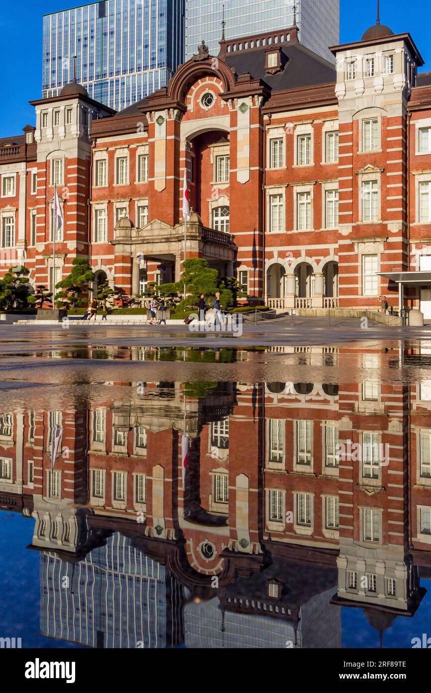 TOKIO, JAPAN - JULI 30 2023: Reflexion des Bahnhofs Tokio in Wasser, das gesprüht wurde, um die Gegend mitten im Sommer zu kühlen Stockfoto