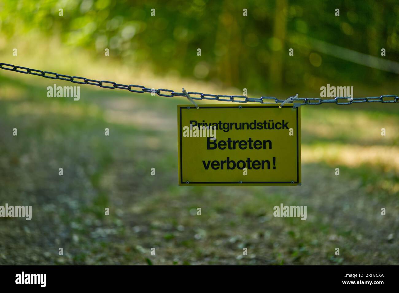 Gelbes Schild mit der Aufschrift „Privates Grundstück, nicht betreten!“ (Deutsch: "Privatgrundstück, Betreten verboten!") Stockfoto