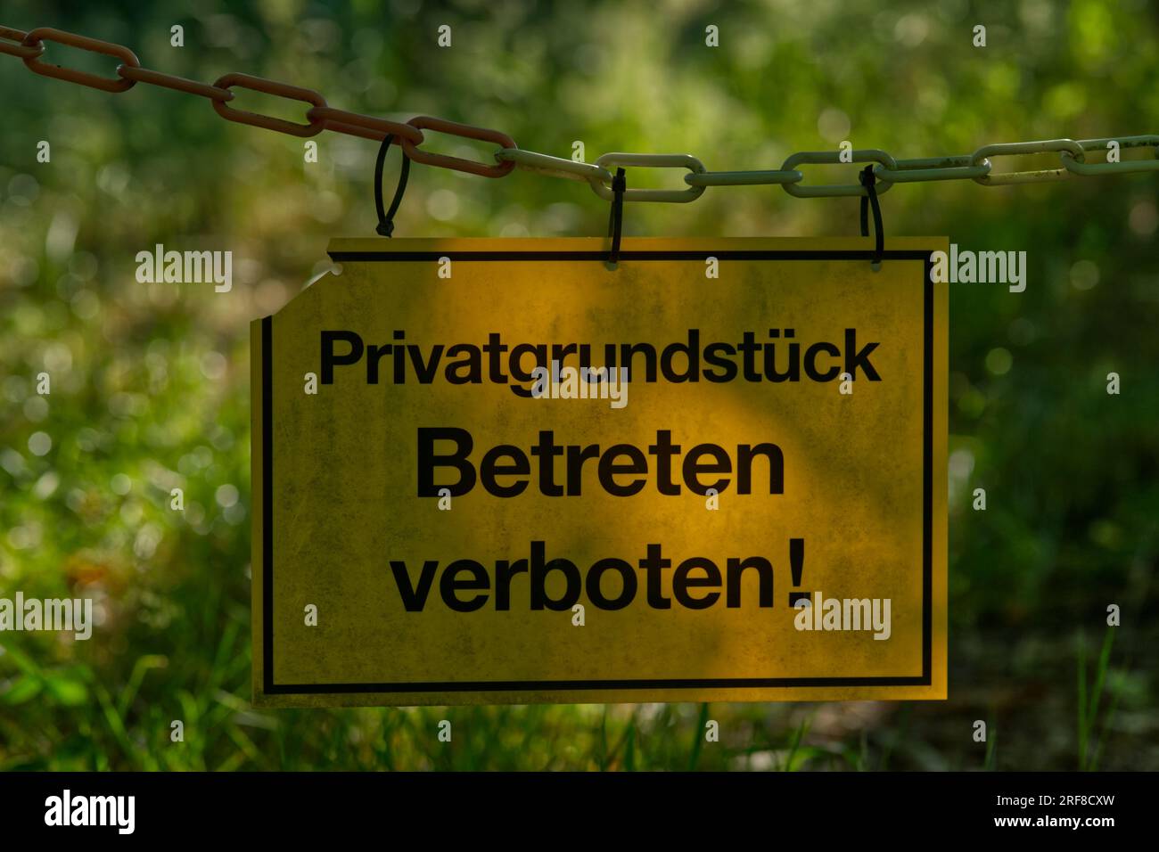 Gelbes Schild mit der Aufschrift „Privates Grundstück, nicht betreten!“ (Deutsch: "Privatgrundstück, Betreten verboten!") Stockfoto