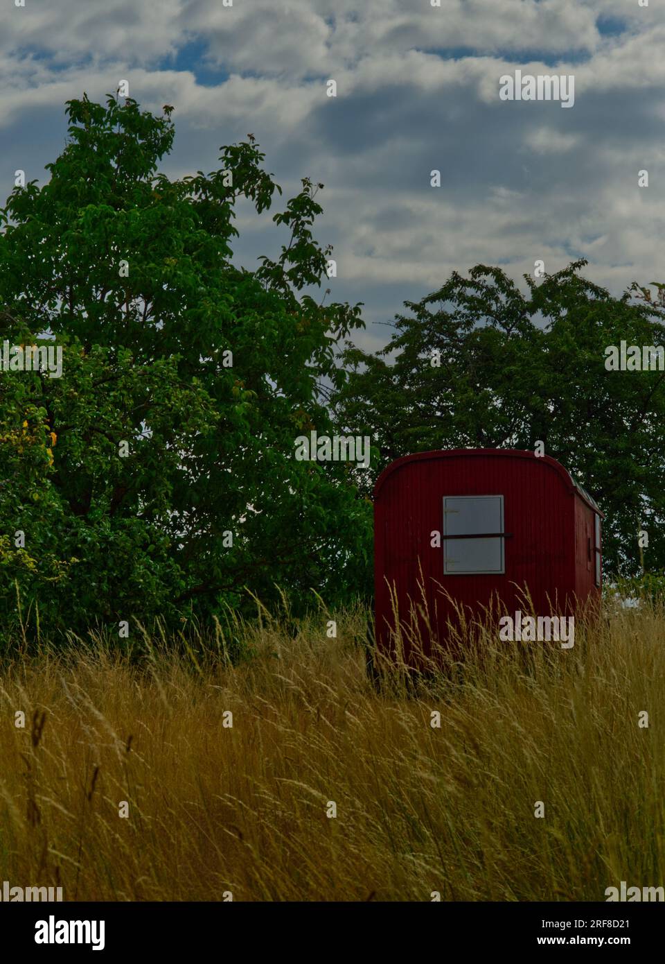 Dunkelroter Bauwagen in einer ländlichen Landschaft Stockfoto