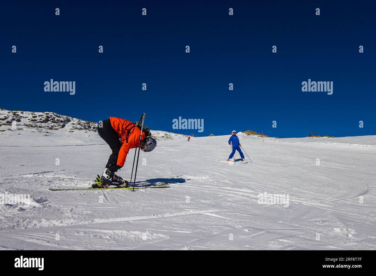 Falcade, Italien - 15. Februar 2023: An einer Skipiste in den Dolomiten. Skifahrer strafft seine Bindung, bevor er den Abstieg beginnt. Perfekt Stockfoto
