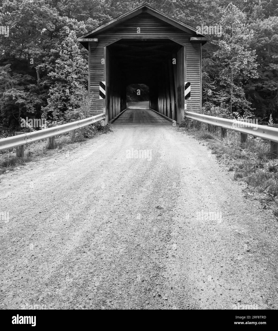 Historische alte verwitterte und abgenutzte hölzerne überdachte Brücke auf der unbefestigten Straße Stockfoto