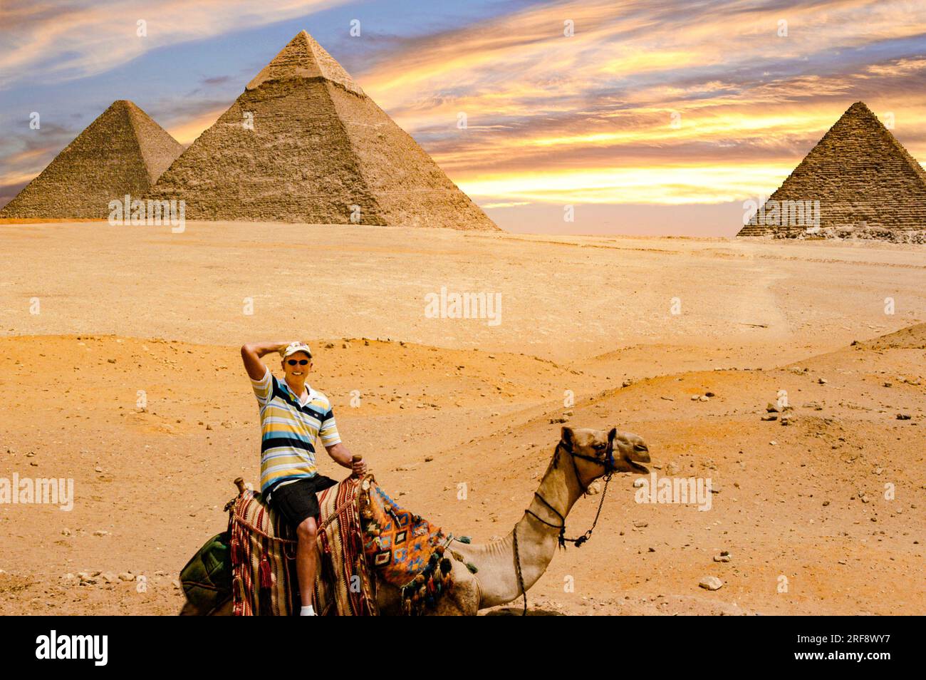 Tourist reitet auf einem Kamel mit den Pyramiden im Hintergrund. Stockfoto